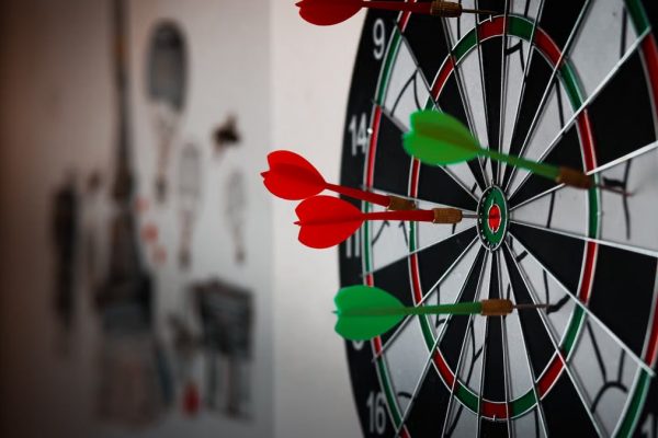 Close-up of a dartboard with multiple darts hitting the target, emphasizing precision and focus.
